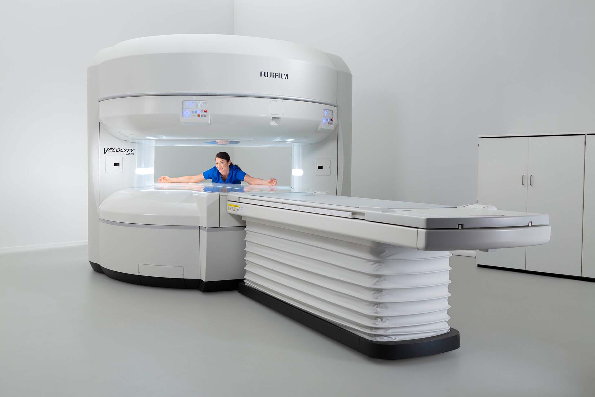 MRI technician with outstretched arms showing space inside open MRI machine MRI technician with outstretched arms showing space inside open MRI machine
