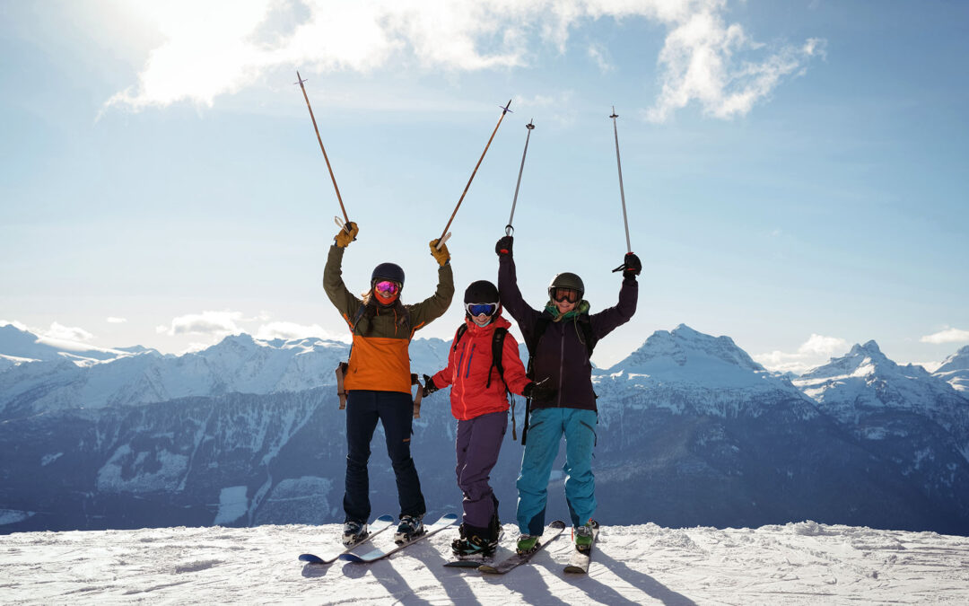 celebrating skiers and snowboarder standing before snow-covered mountain