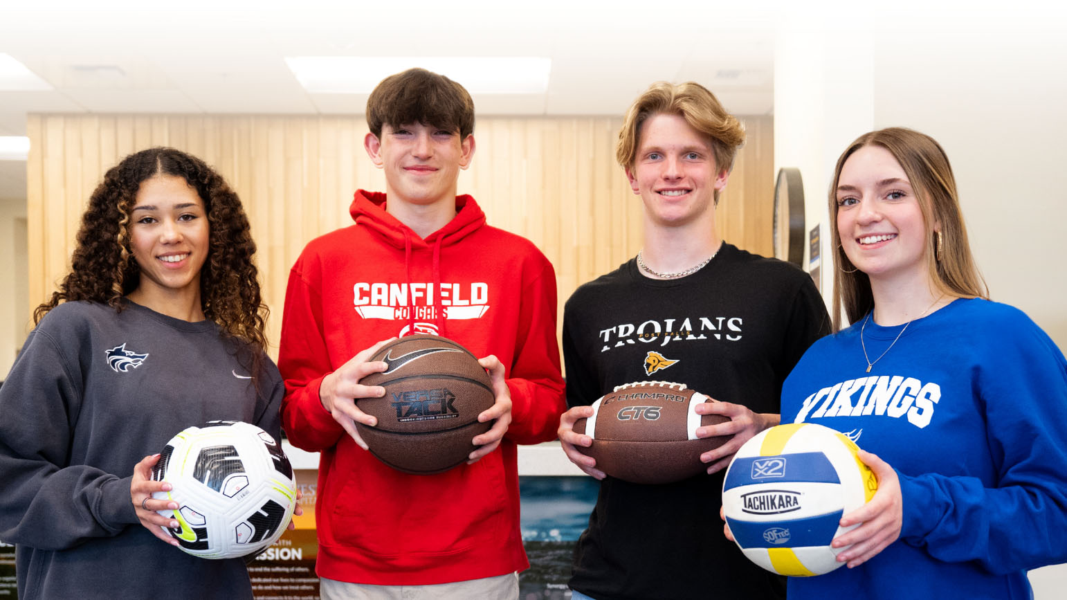 Free-Sports-Physicals smiling student athletes in a roll, holding respective sports balls